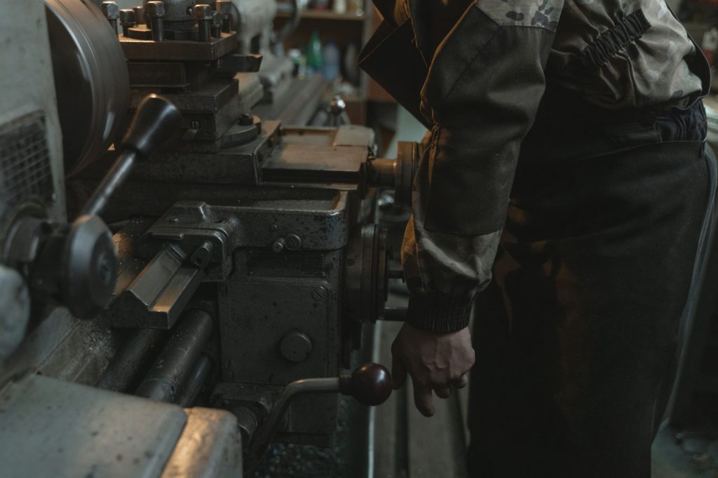 Close-up of a craftsman working on a lathe machine in an indoor workshop setting.