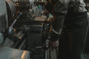 Close-up of a craftsman working on a lathe machine in an indoor workshop setting.
