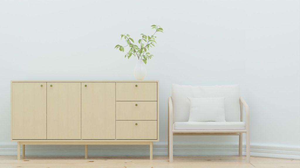 Elegant minimalist interior design featuring a wooden sideboard and armchair with greenery.