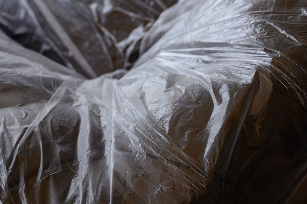 Detailed view of furniture wrapped in protective plastic for moving.