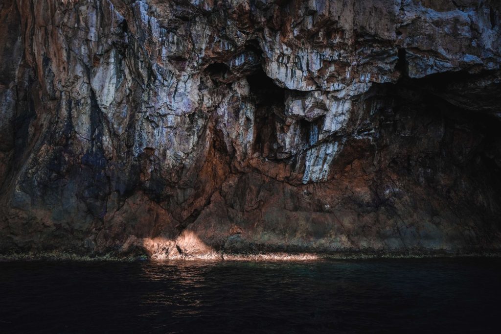 Sunlight reflects on the sea and rugged coastal cliff, creating a dramatic scene.