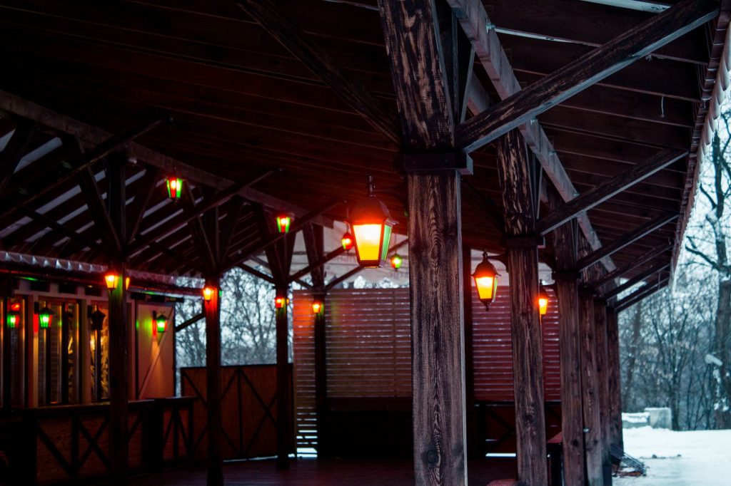 Cozy wooden shed with glowing lanterns on a snowy winter day, providing a warm ambiance.