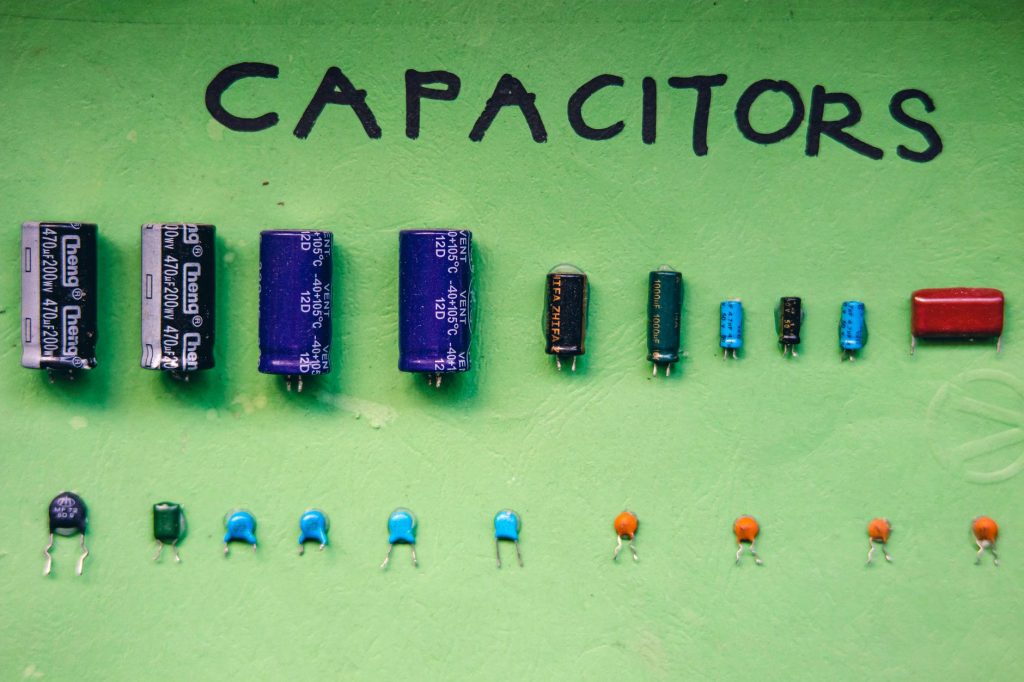 Top view layout abundance of aluminum electrolytic capacitors of varying capacity with ceramic discs placed on green background with inscription
