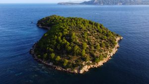 Stunning aerial shot of a lush green island surrounded by the blue Mediterranean sea.